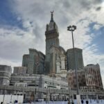 View of the impressive Abraj Al Bait Towers in Mecca, Saudi Arabia under a cloudy sky.